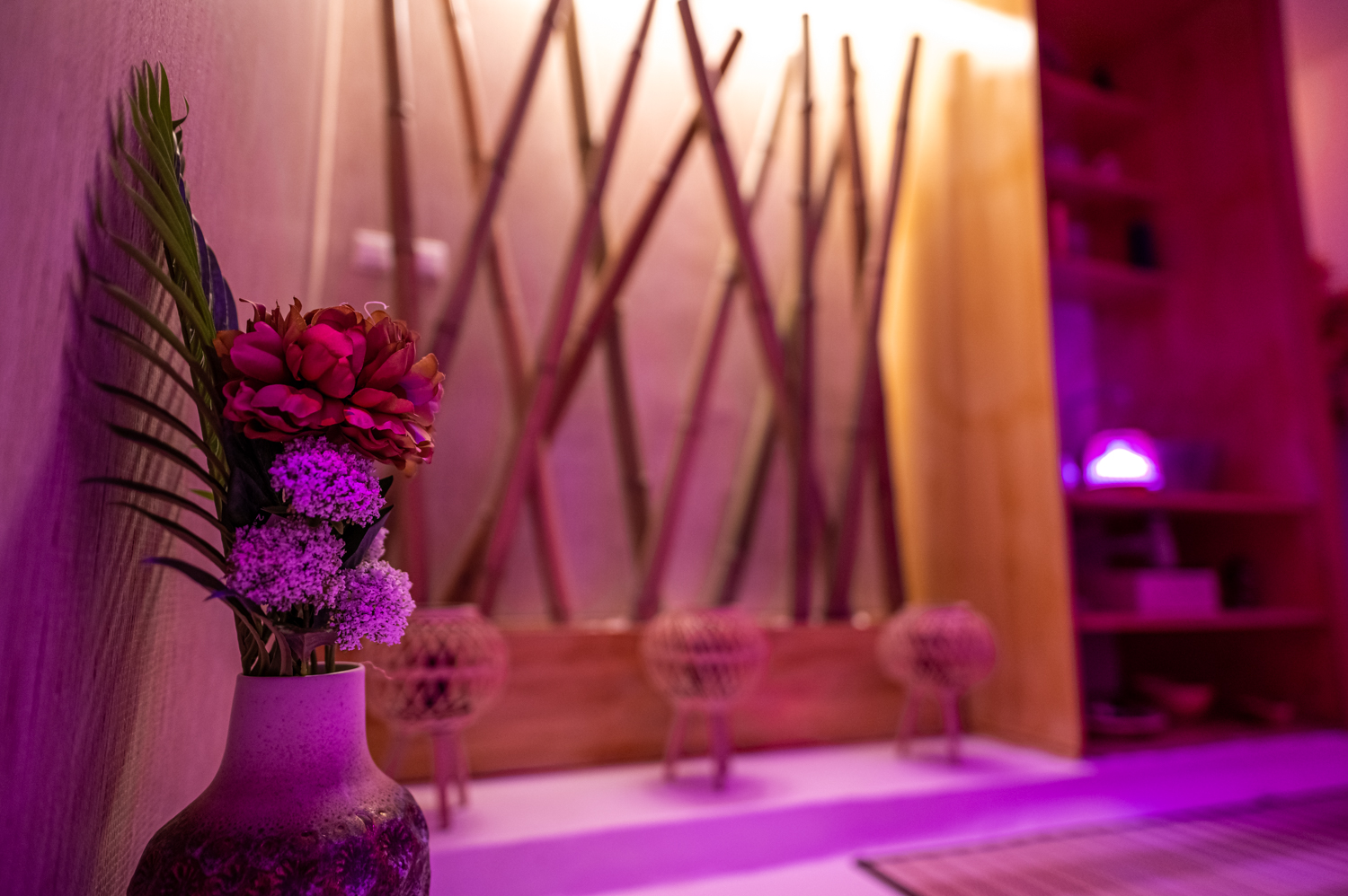 Vaso com flores num ambiente relaxante de spa com iluminação roxa.